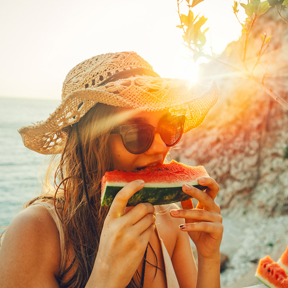 Woman eating watermelon by the ocean